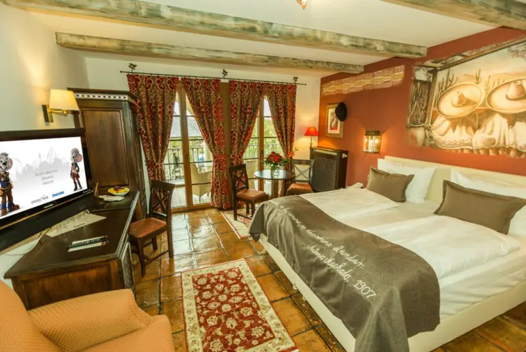 A hotel room with a double bed and red curtains in the Spanish style